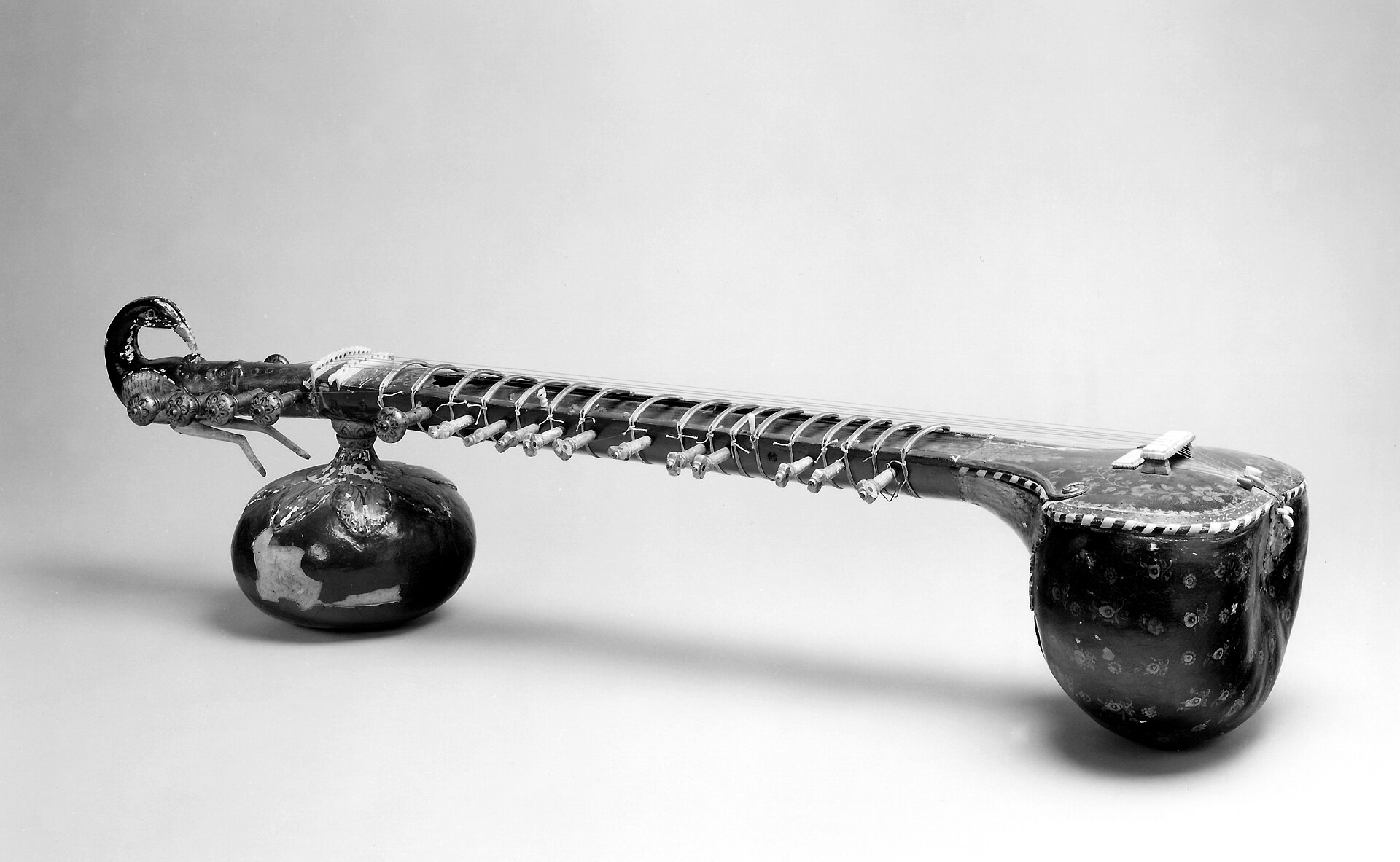Museum photograph of a sitar, showing the carved neck and strings
